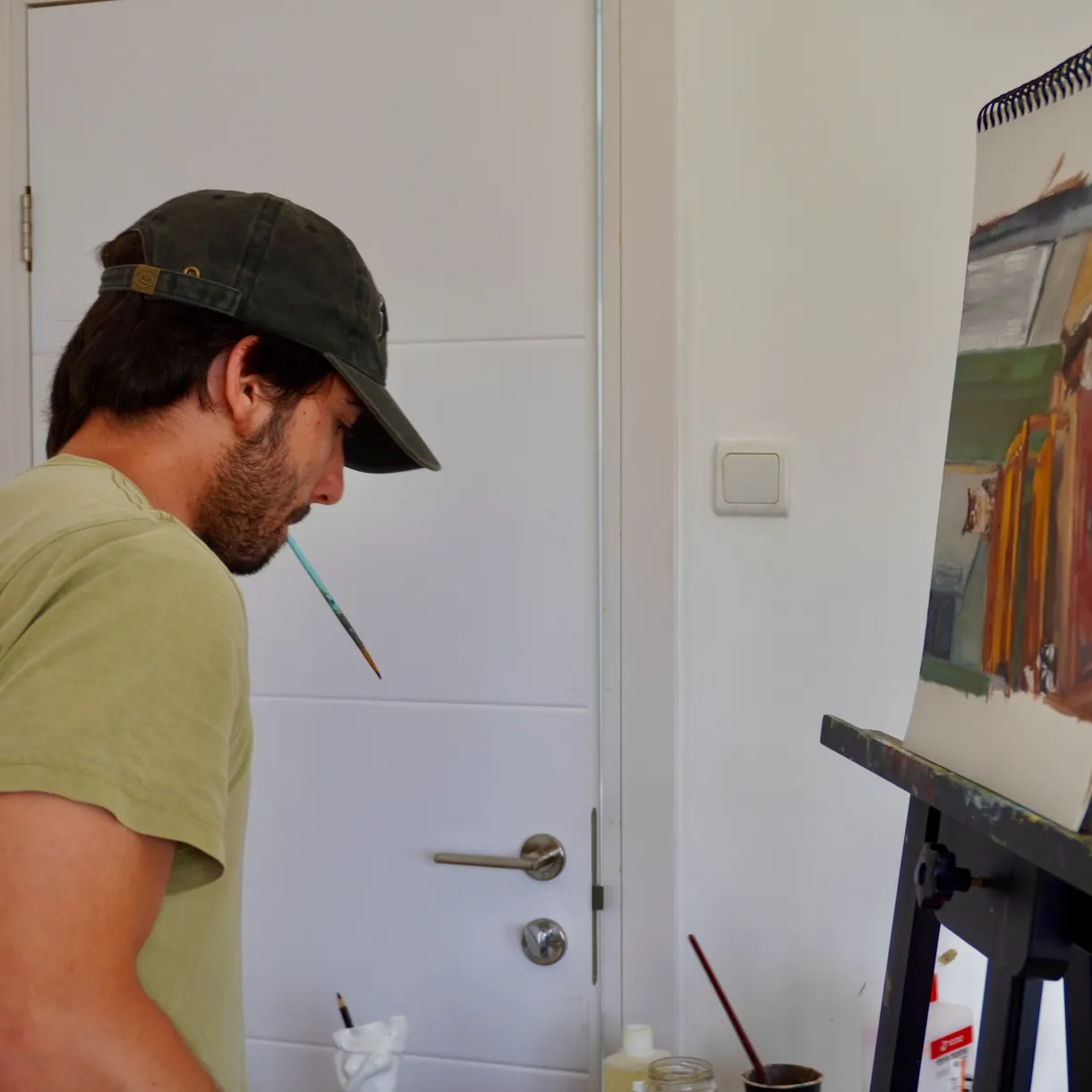 Yoav Mendelson painting at an easel in his workspace.
