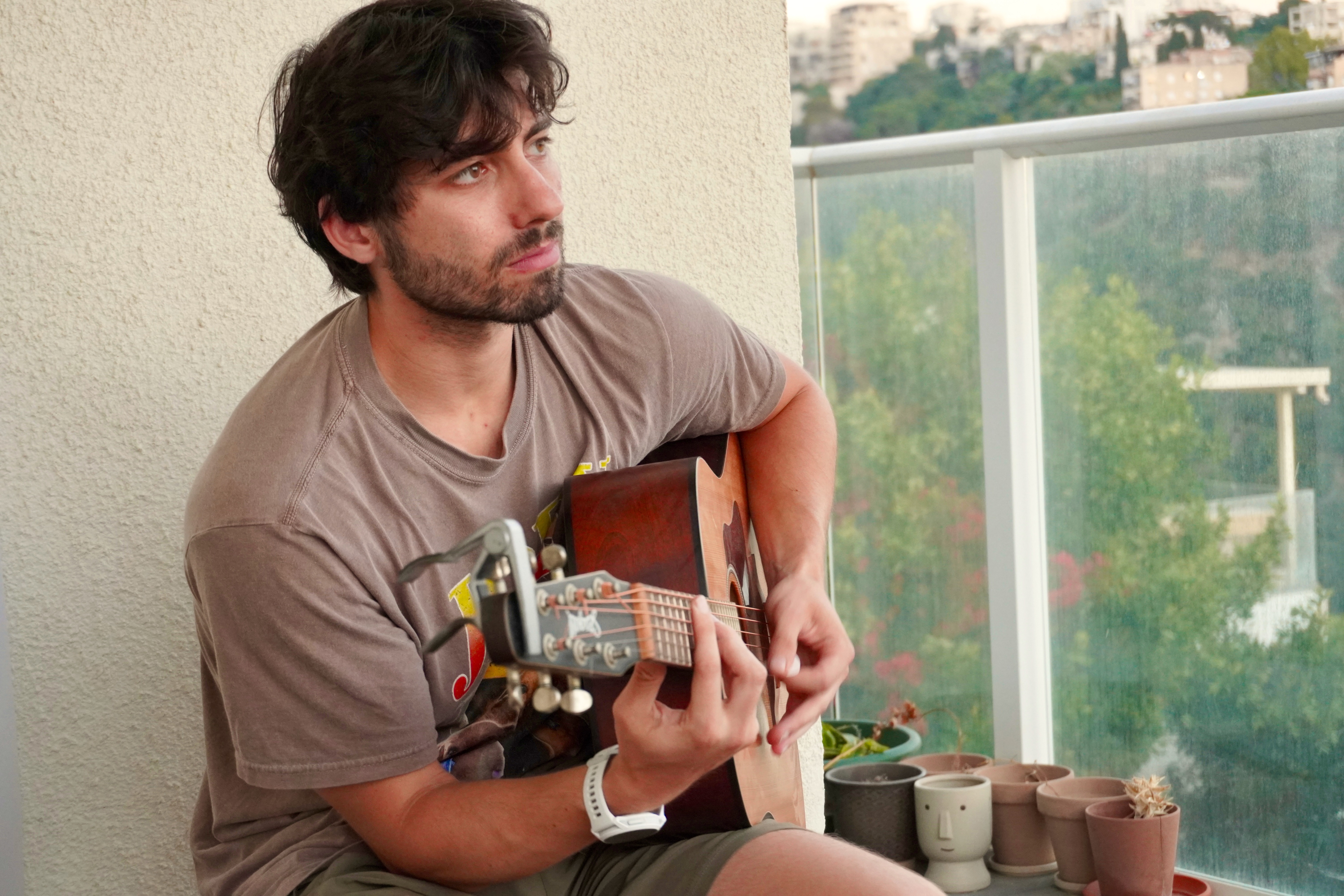 Yoav Mendelson seated with an acoustic guitar.